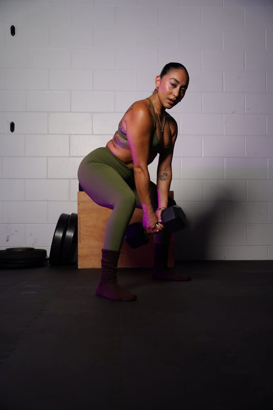 A confident woman wearing sleek ROCFIT activewear performing precise upper body exercises for women with dumbbells on a studio mat.