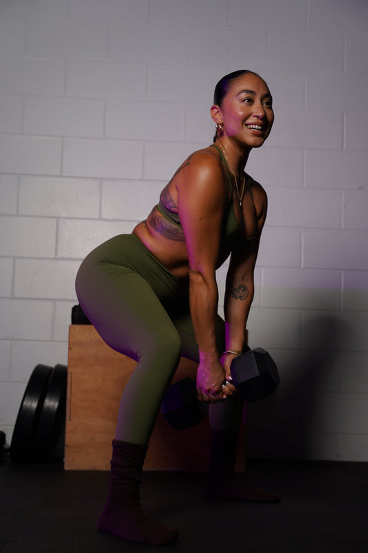 A woman smiling while learning how to stay consistent with workouts.